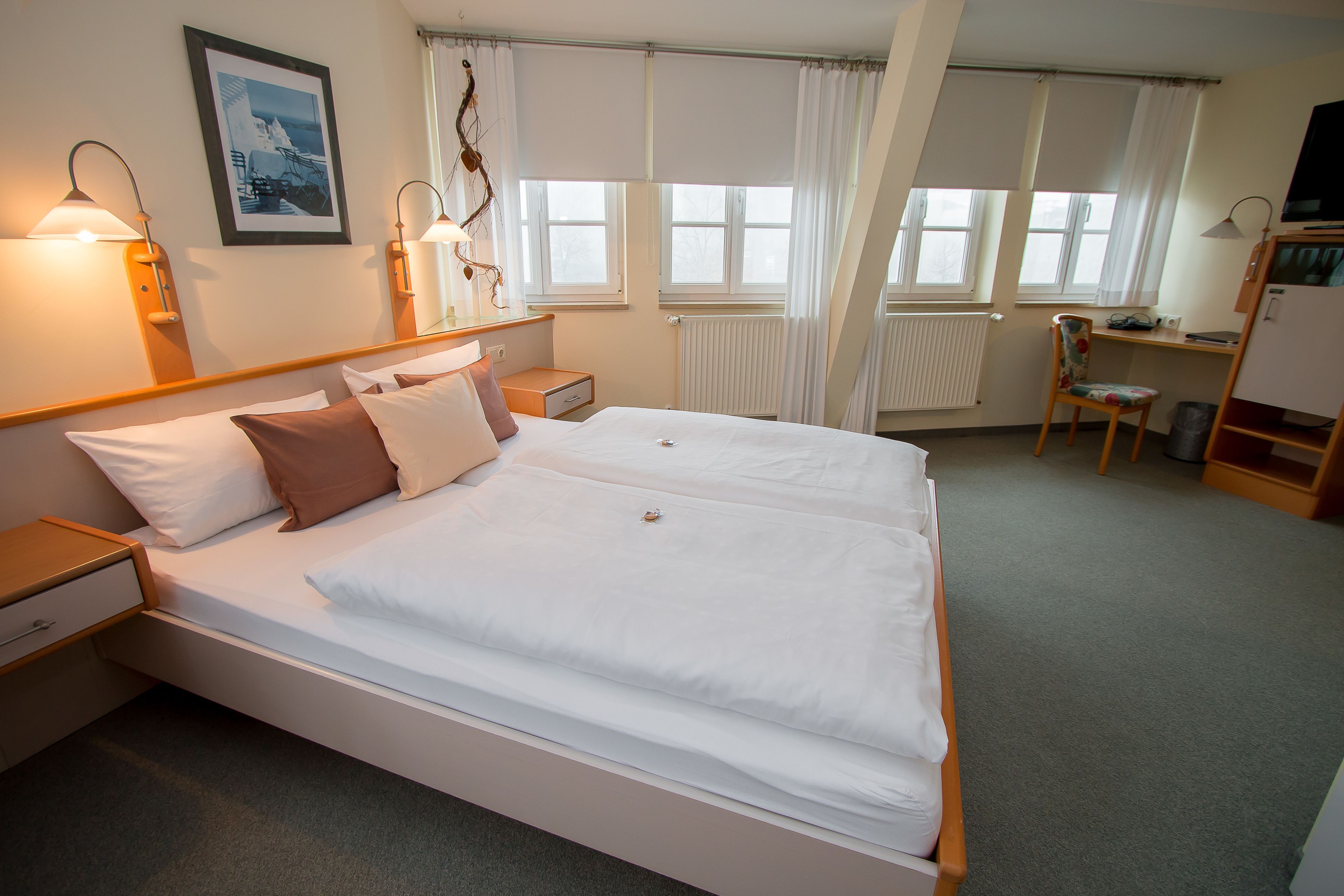 A neatly arranged hotel room with a large bed, bedside tables, a desk, and a chair.