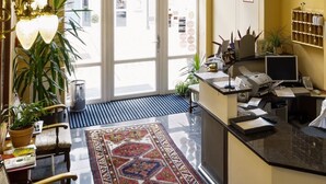 Un vestíbulo de hotel con una recepción, un amplio ventanal de arco y una alfombra estampada.