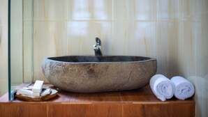 A stone basin sink with a faucet, a wooden tray with soap, and rolled towels on a wooden counter. - Mahaloka Valley (Penida Island)