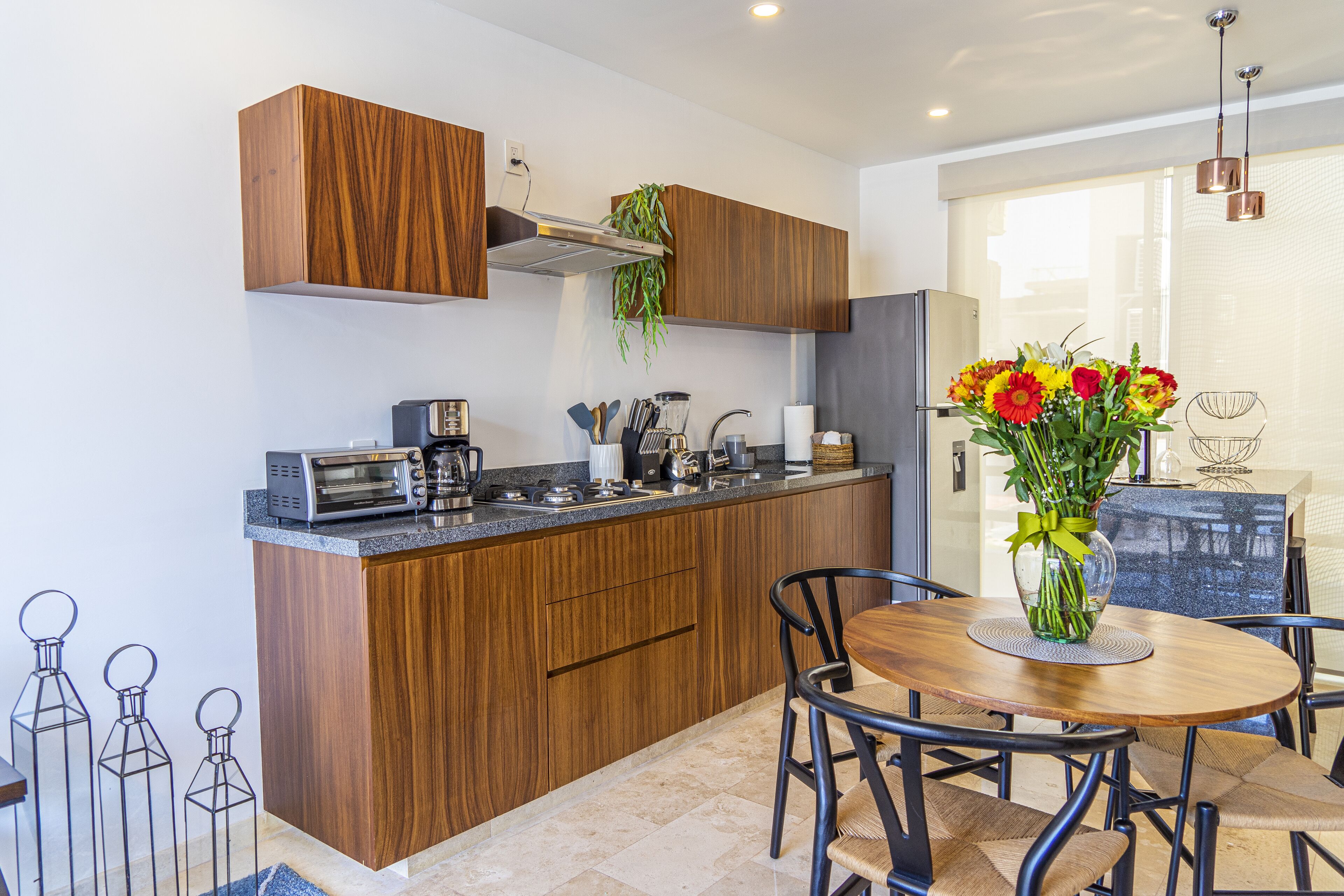 Een moderne keuken met houten kastjes, een inbouwoven en een eethoek met een ronde tafel en stoelen.