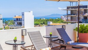 A rooftop terrace with lounge chairs, a table, and an umbrella. - Tres Marias Luxury Suites - Adults Only (Puerto Vallarta)
