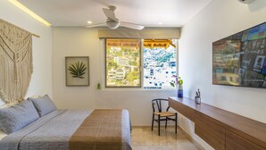 A bedroom with a bed, a desk, and a window with a view of buildings. - Tres Marias Luxury Suites - Adults Only (Puerto Vallarta)