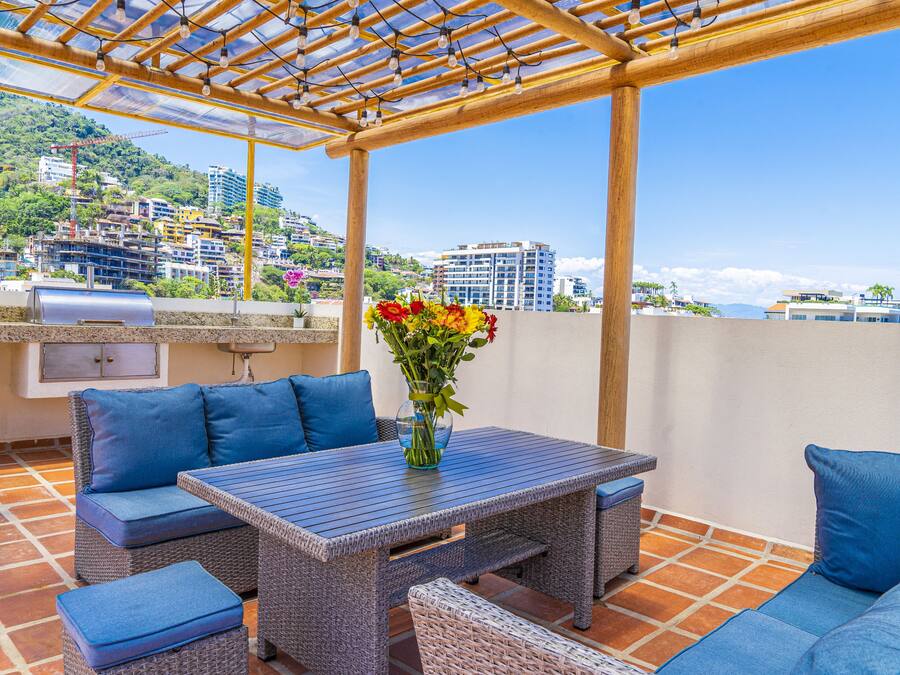 An outdoor patio with wicker furniture, a table, and a grill.