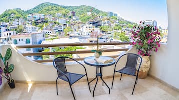 Een balkon met twee stoelen, een tafeltje en een bloempot.