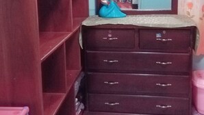 Ein Zimmer mit Holzschrank, Spiegel und Fliesenboden.