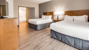 Een hotelkamer met twee bedden, een houten hoofdbord, een nachtkastje met een lamp en een houten vloer.