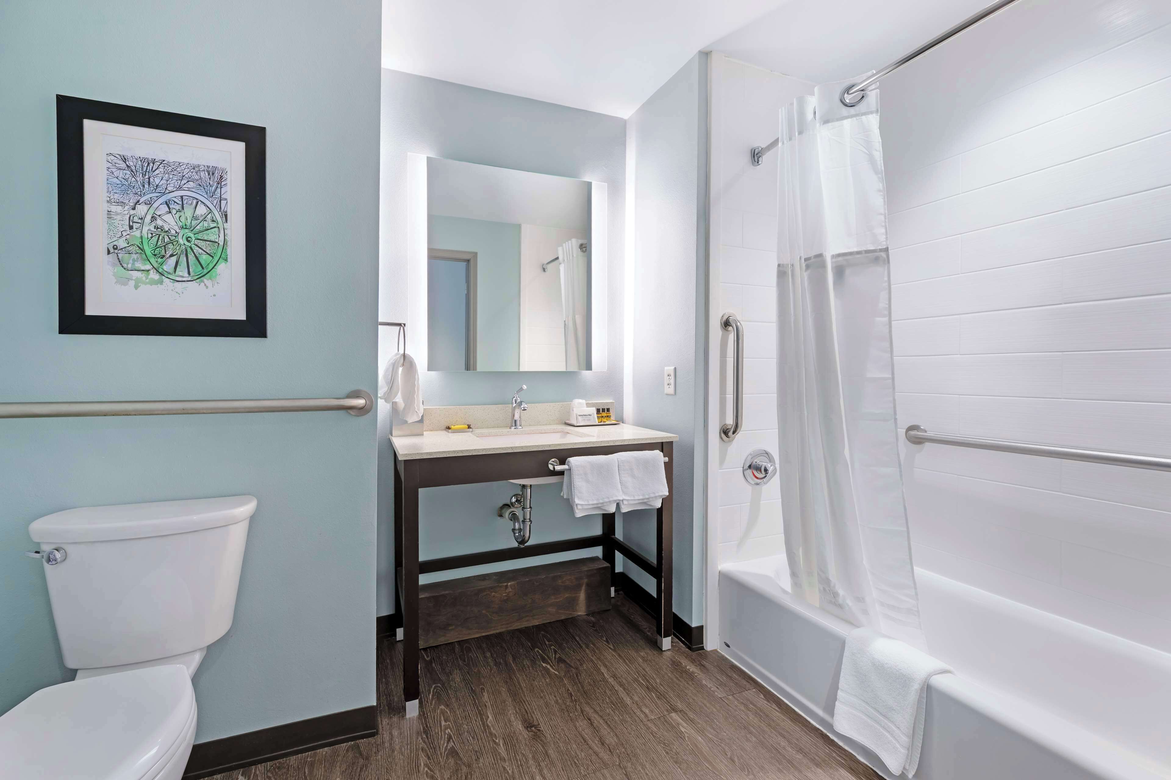 A bathroom with a toilet, sink, mirror, and bathtub.