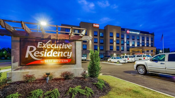 Een Executive Residency by Best Western met een bord, parkeerplaats en een meerlaags gebouw op de achtergrond.