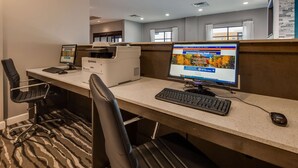 Een hotel werkplek met een bureaubcomputer, printer en twee kantoorstoelen.