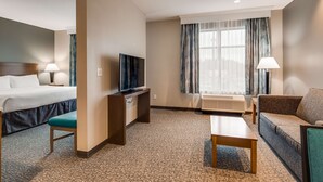 Een hotelkamer met een bed, een bureau met een televisie, een bank en een raam met gordijnen.