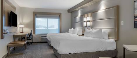 Una habitación de hotel moderna con una cama grande, un escritorio y una silla. Hay una ventana con vistas a la ciudad.
