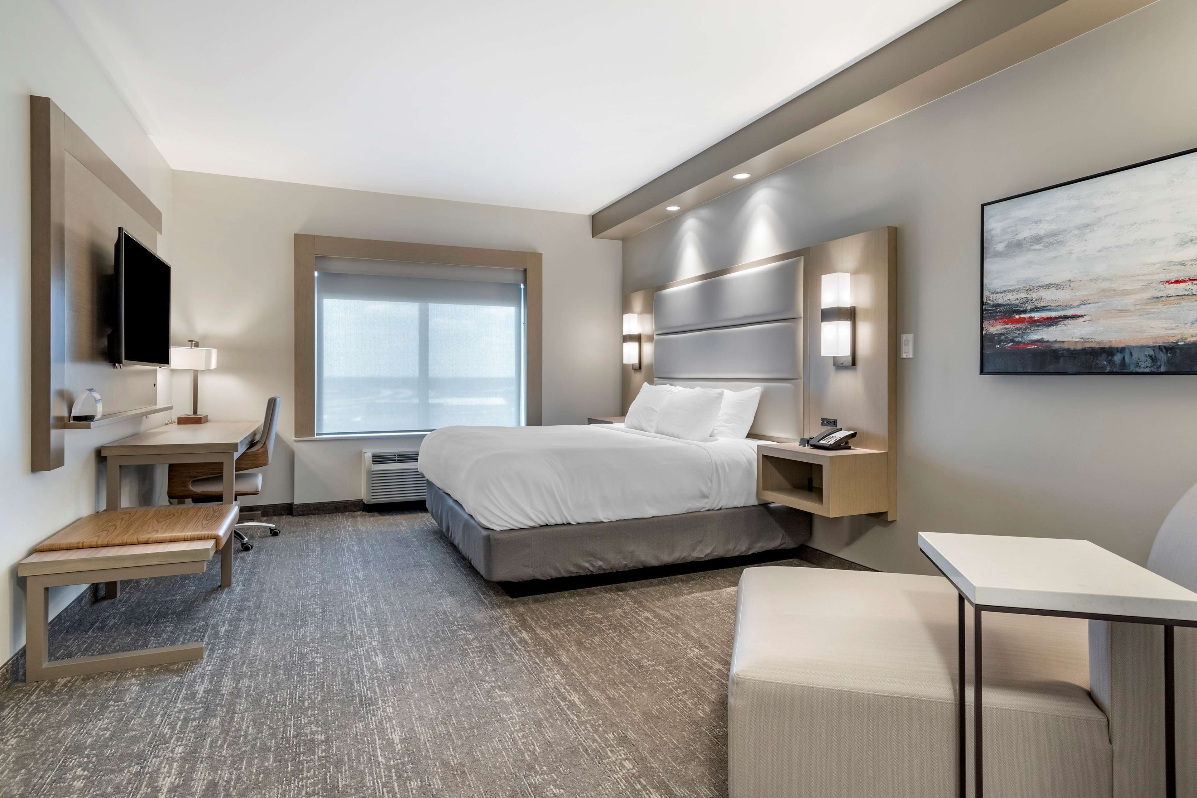 Une chambre d’hôtel moderne équipée d’un grand lit, d’un bureau, d’une chaise et d’un téléviseur.