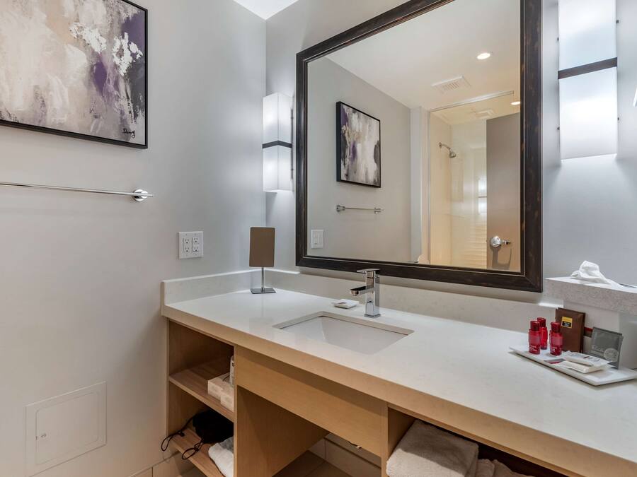 A modern bathroom with a large mirror, a sink, and a towel rack.