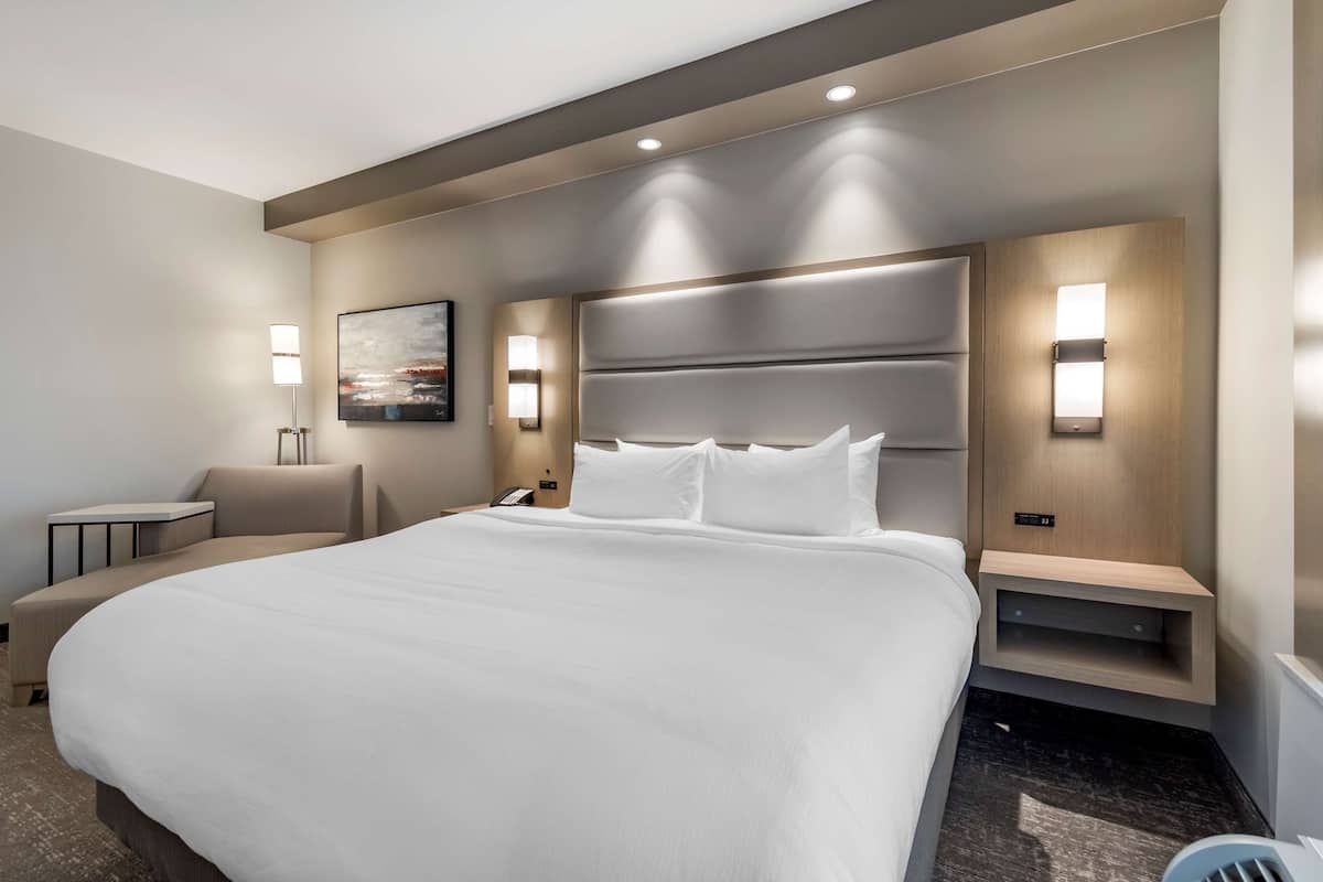 A modern hotel room with a large bed, bedside tables, a desk, and a chair.