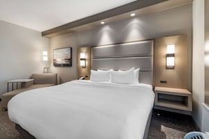 Una habitación de hotel moderna con una cama grande, mesitas de noche, un escritorio y una silla.