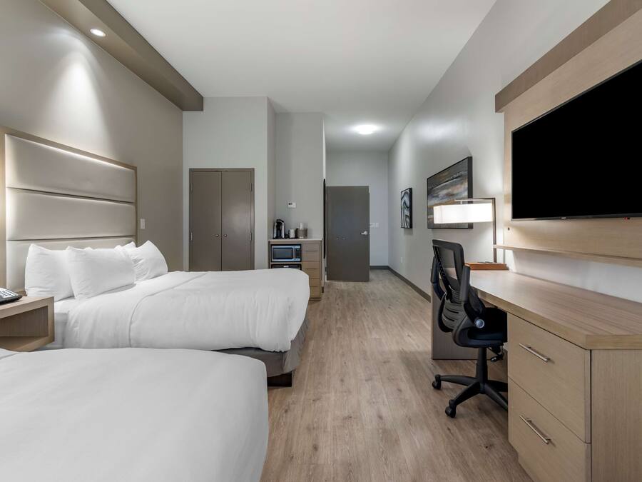 Ett hotellrum med två sängar, ett skrivbord, en platt-TV och en skrivbordslampa.