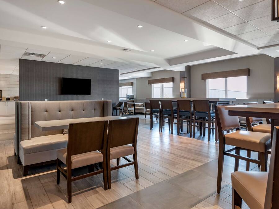 A modern hotel lobby with a seating area, a bar, and a dining space.