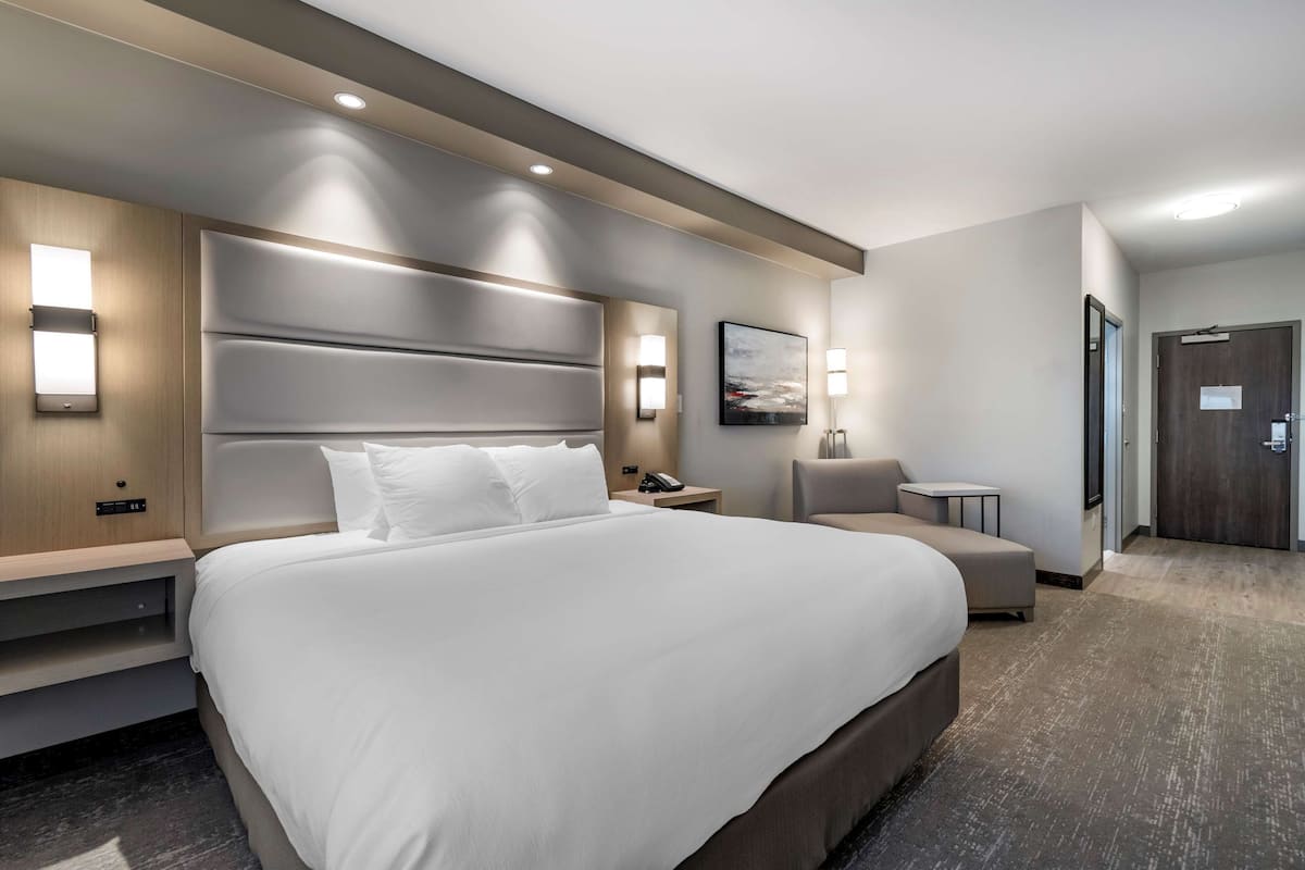 Ein modernes Hotelzimmer mit einem großen Bett, Nachttischen, einem Schreibtisch und einem Stuhl.