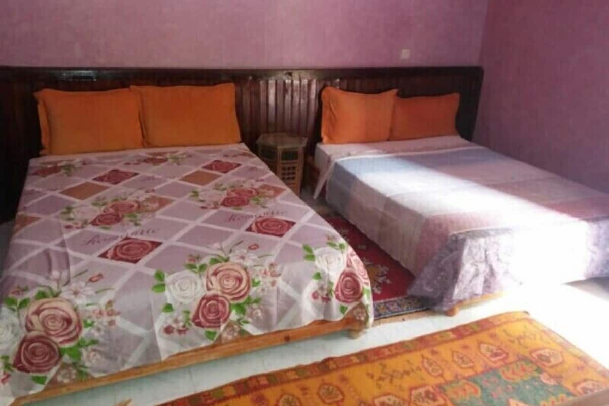 A bedroom with two beds, one larger and one smaller, both with orange bedding.