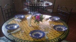 A round dining table with blue and yellow patterned tablecloth, surrounded by chairs. - Maison d'Hôtes au Jardin de Tamnougalt (Mezguita)