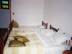 A standard hotel room with a single bed, checkered bedspread, and wooden headboard.