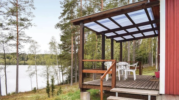 A wooden deck with a glass roof overlooking a lake, surrounded by trees. - Cozy home in Bodafors with kitchen (Bodafors)