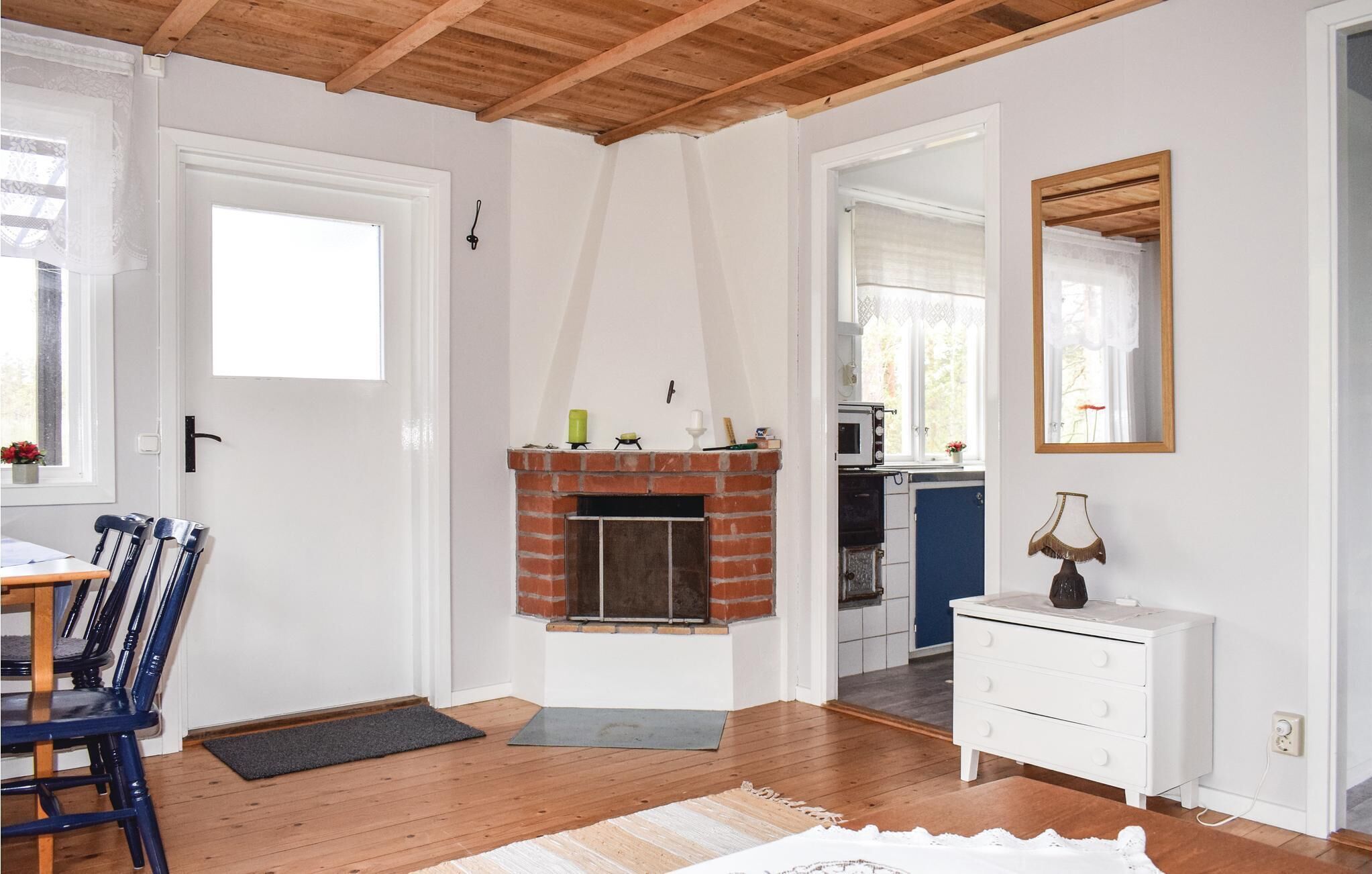 Quarto com lareira, piso de madeira, penteadeira branca e área de refeições com cadeiras.