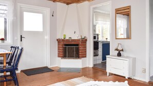 A room with a fireplace, wooden flooring, a white dresser, and a dining area with chairs. - Cozy home in Bodafors with kitchen (Bodafors)