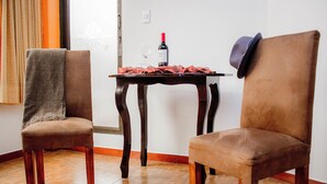 Dos sillones marrones tapizados con una mesa en el centro, una botella de vino y una copa sobre la mesa.