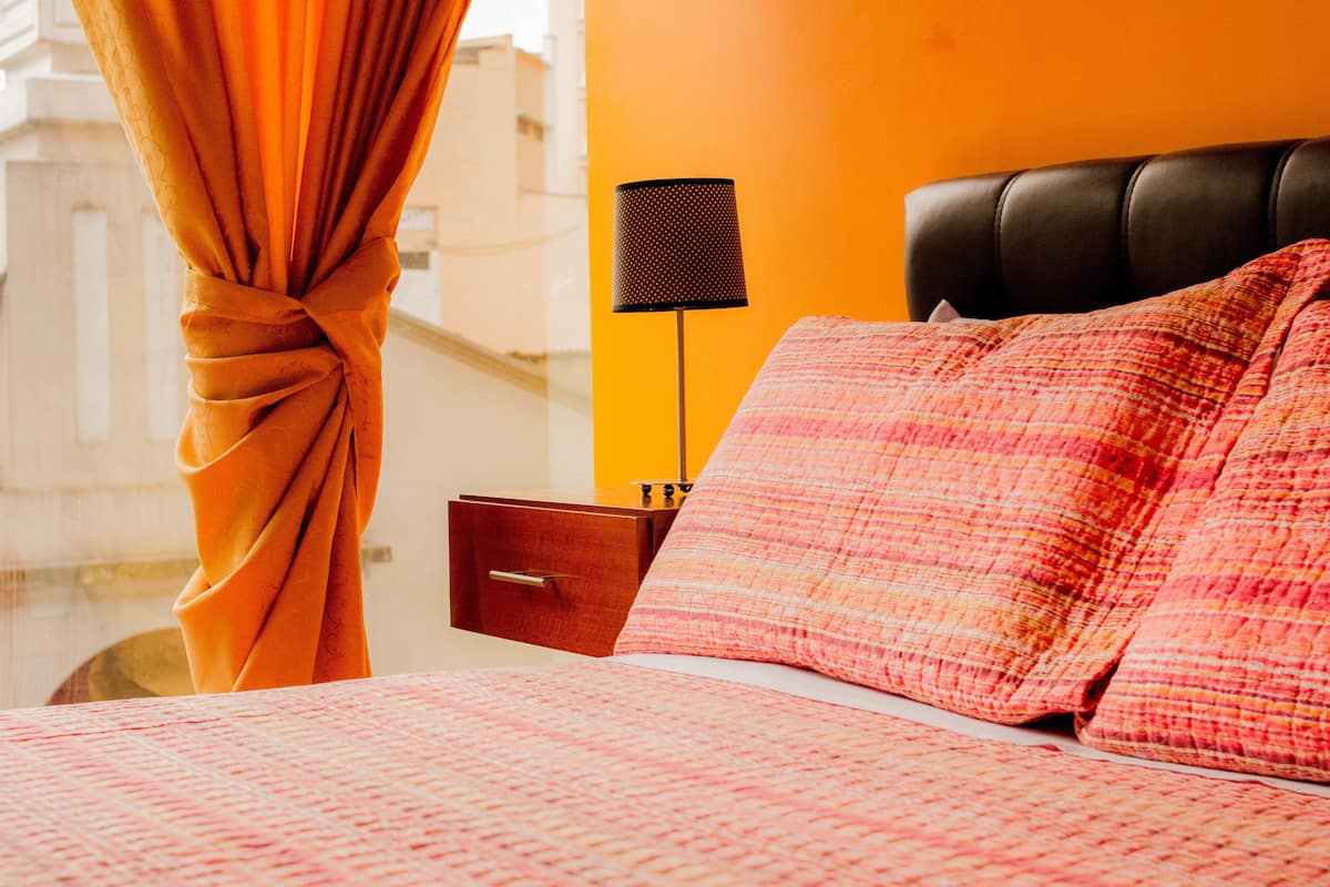 Une chambre d’hôtel avec un lit, une table de chevet, une lampe et une vue sur la ville.