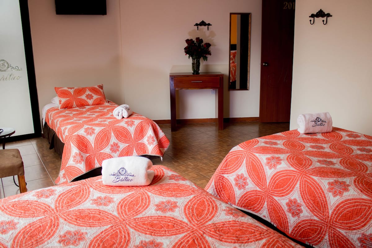 Une chambre d’hôtel avec deux lits, une table de chevet en bois, un vase avec des fleurs et une porte portant le numéro 201.