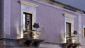 Een gebouw met twee balkons, elk met een stoel en een bloempot.