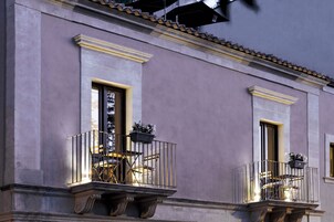 Un edificio con dos balcones, cada uno con una silla y una planta en maceta.