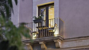 Een balkon met een hekwerk, een raam en een bloempot.