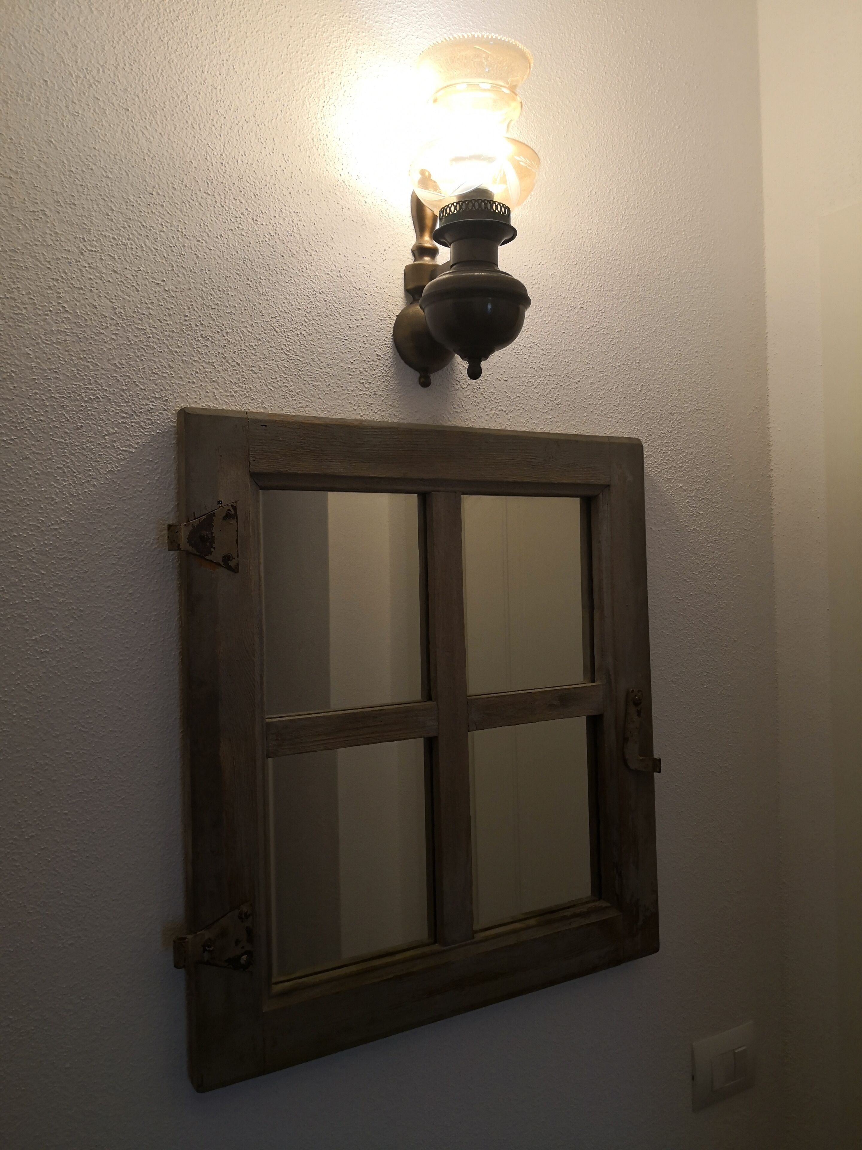Une fenêtre à cadre en bois, avec un luminaire placé au-dessus.