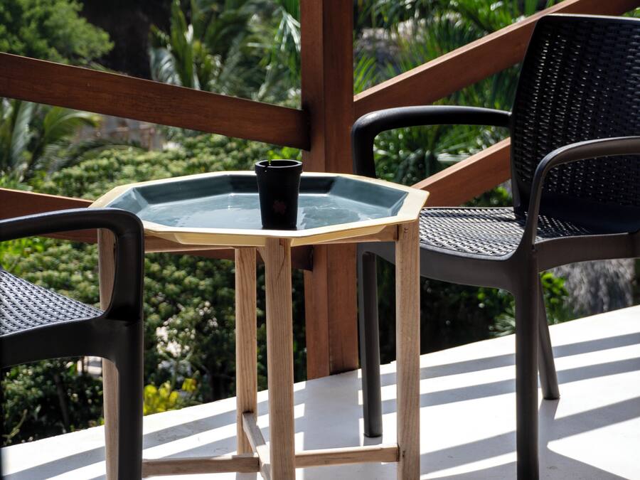 A balcony with a glass table, two chairs, and a potted plant.