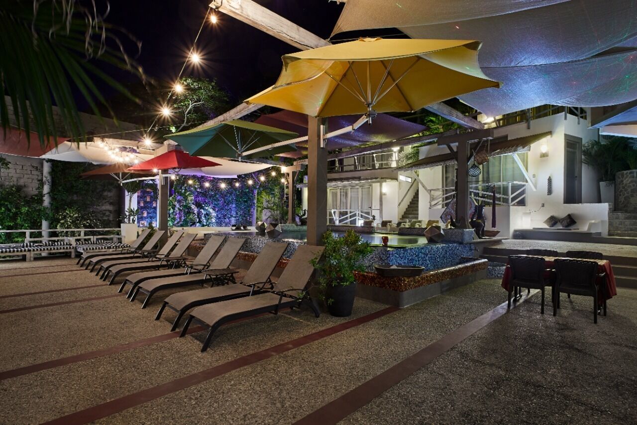 A rooftop lounge area with sun loungers, umbrellas, and a pool.