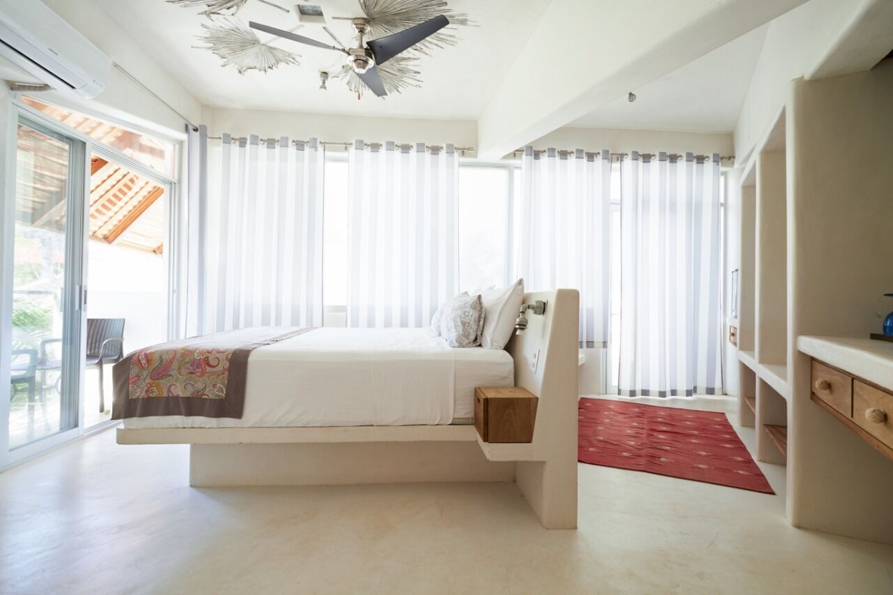 A modern bedroom with a bed, a ceiling fan, and a view of the outdoors.