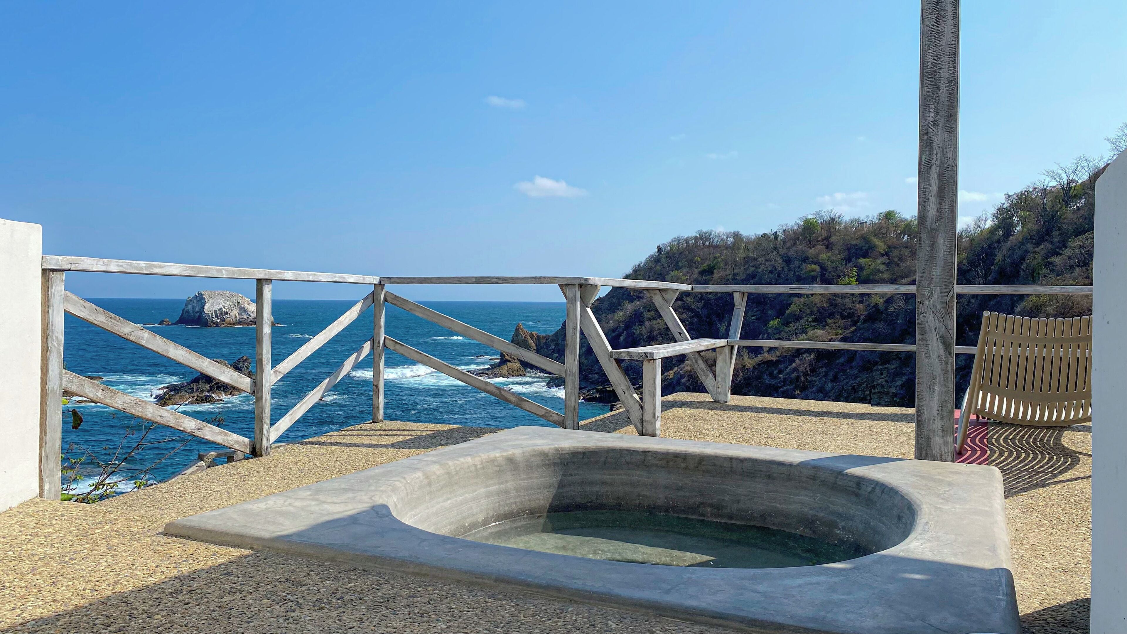 A wooden deck with a hot tub overlooking the ocean.