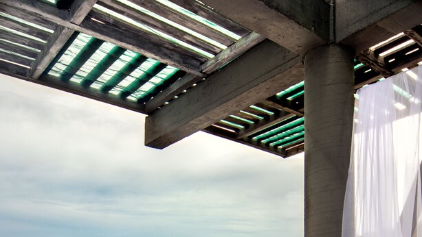 A balcony with a bed, a view of the ocean, and a rocky coastline.
