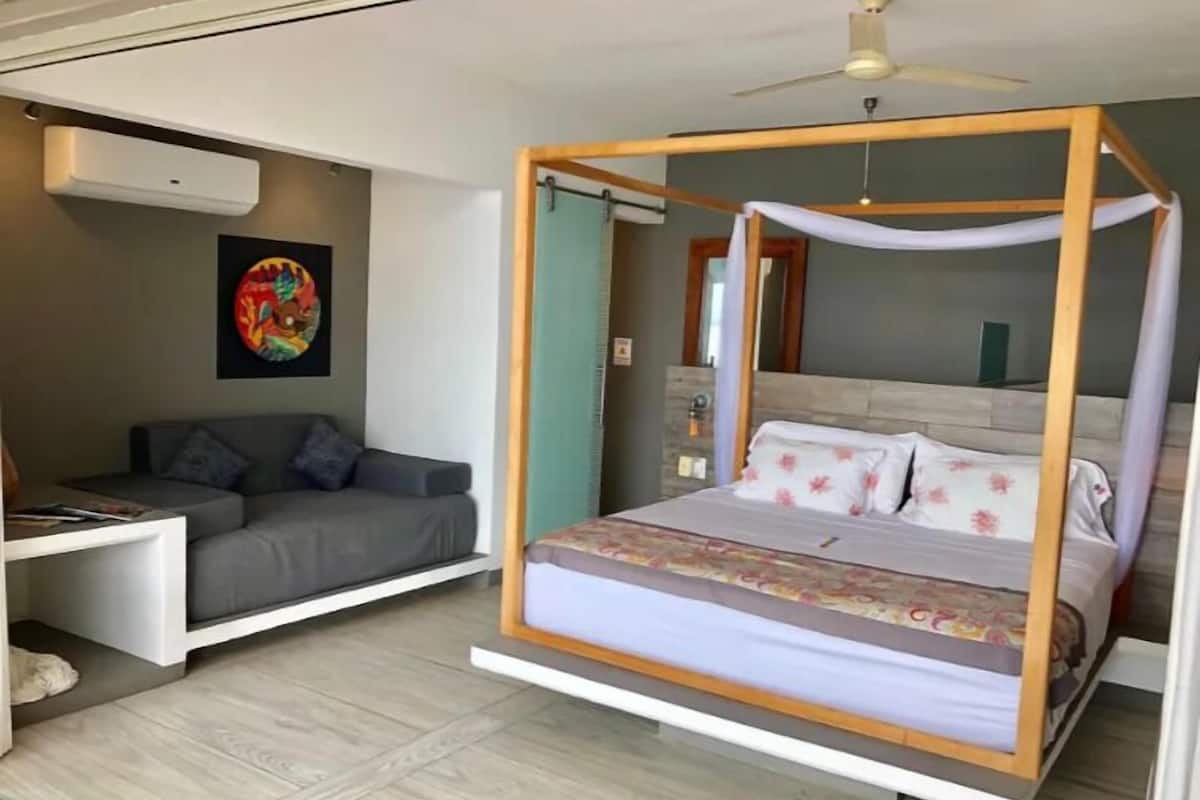 A bedroom with a bed, a sofa, and a desk.