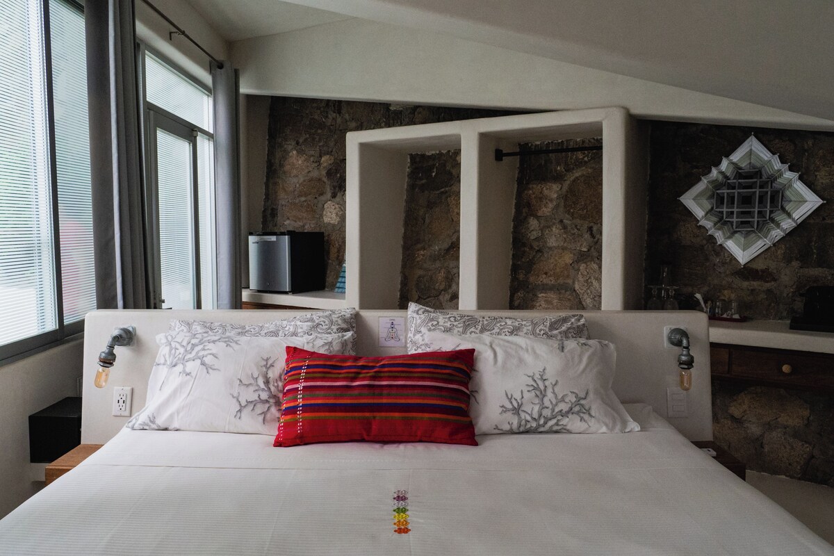A bedroom with a bed, a stone wall, a television, and a decorative item on the wall.