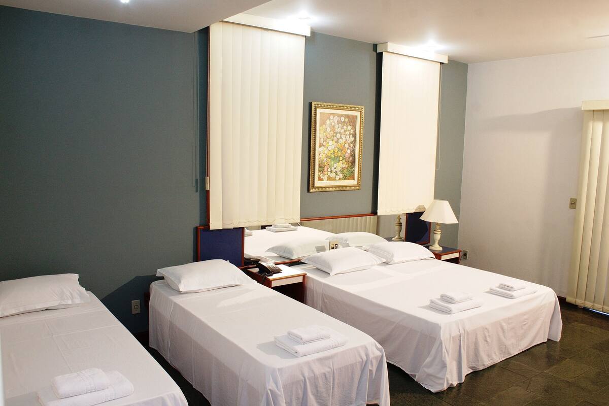 Ein Hotelzimmer mit zwei Einzelbetten, einem Nachttisch mit Lampe, einem Telefon und einem gerahmten Bild an der Wand.