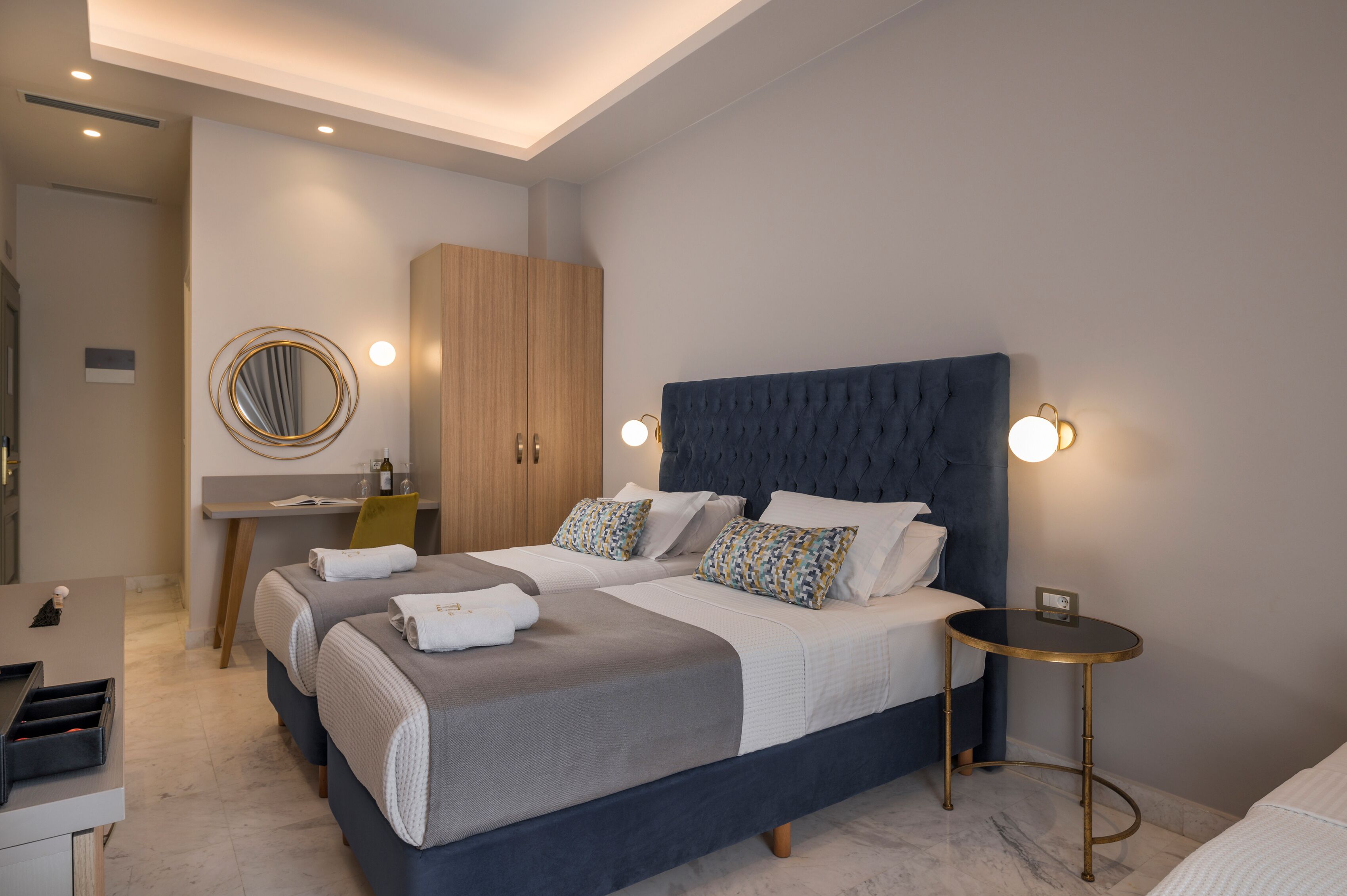 A modern hotel room with a large bed, bedside tables, a desk, and a wardrobe.