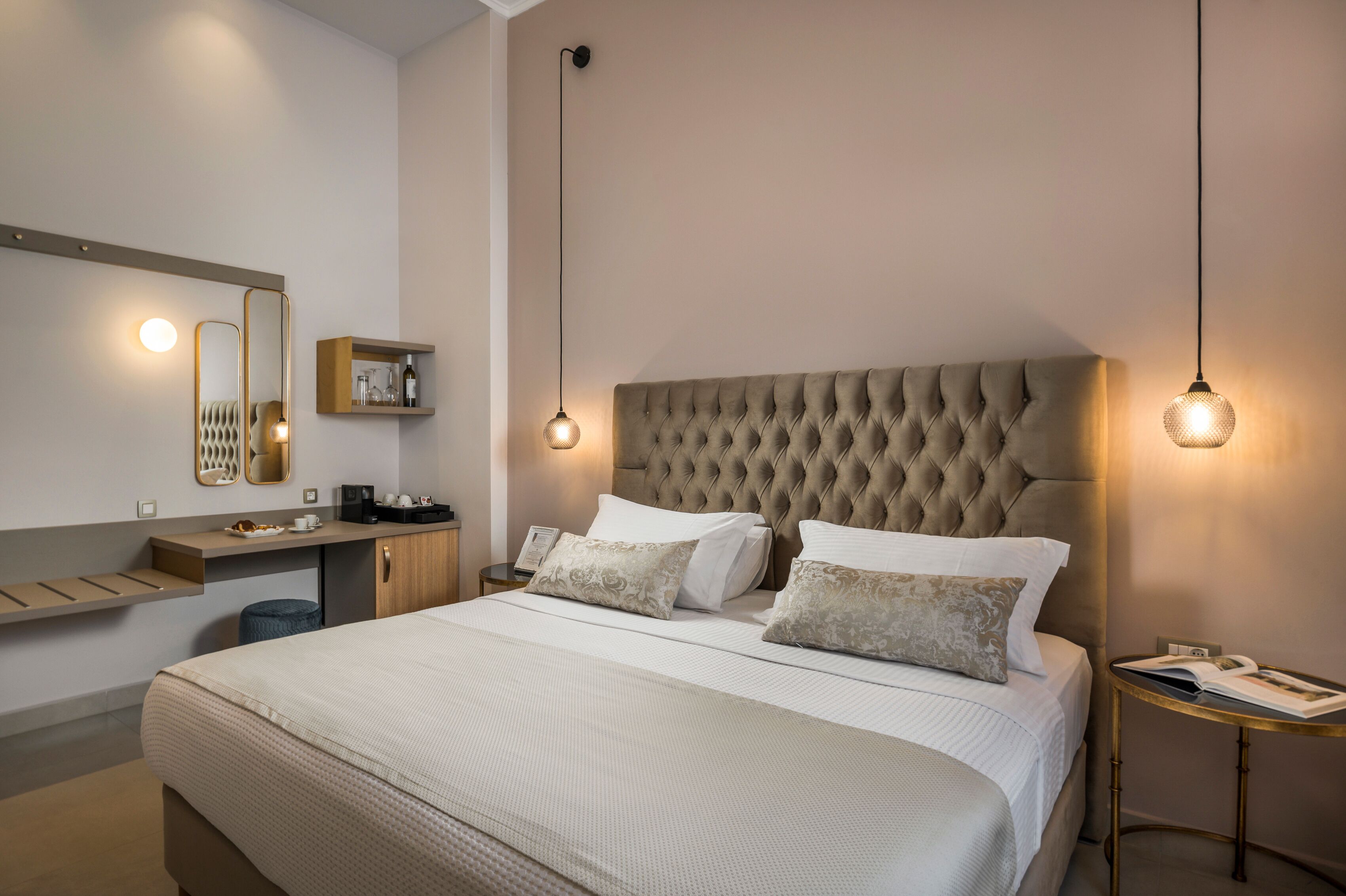 A neatly arranged hotel room with a large bed, bedside tables, a mirror, and a shelf with toiletries.