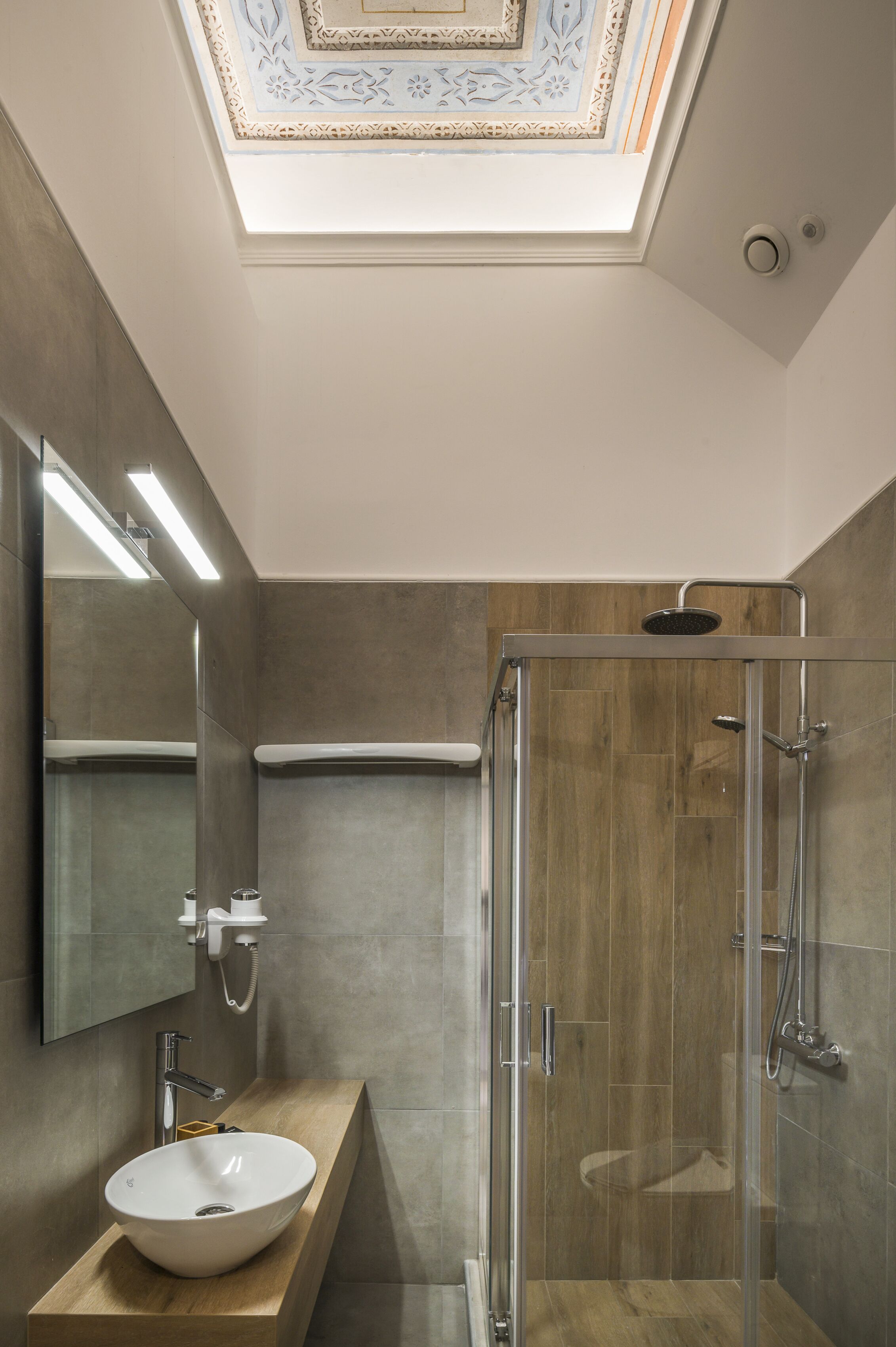 Ein modernes Badezimmer mit Oberlicht, einer Glaskabine für die Dusche und einem Holzbadezimmer-Möbel.