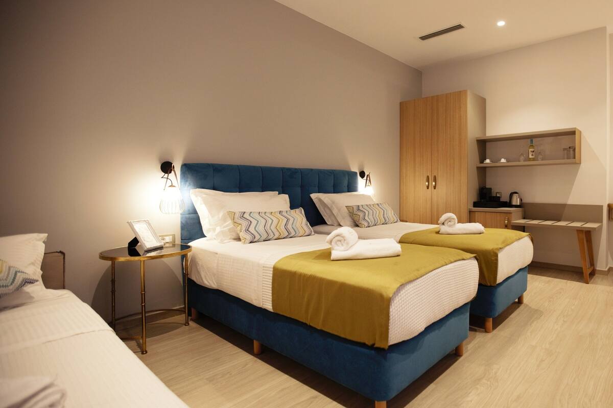 Une chambre d’hôtel avec deux lits, un bureau, une chaise, une armoire et un miroir.