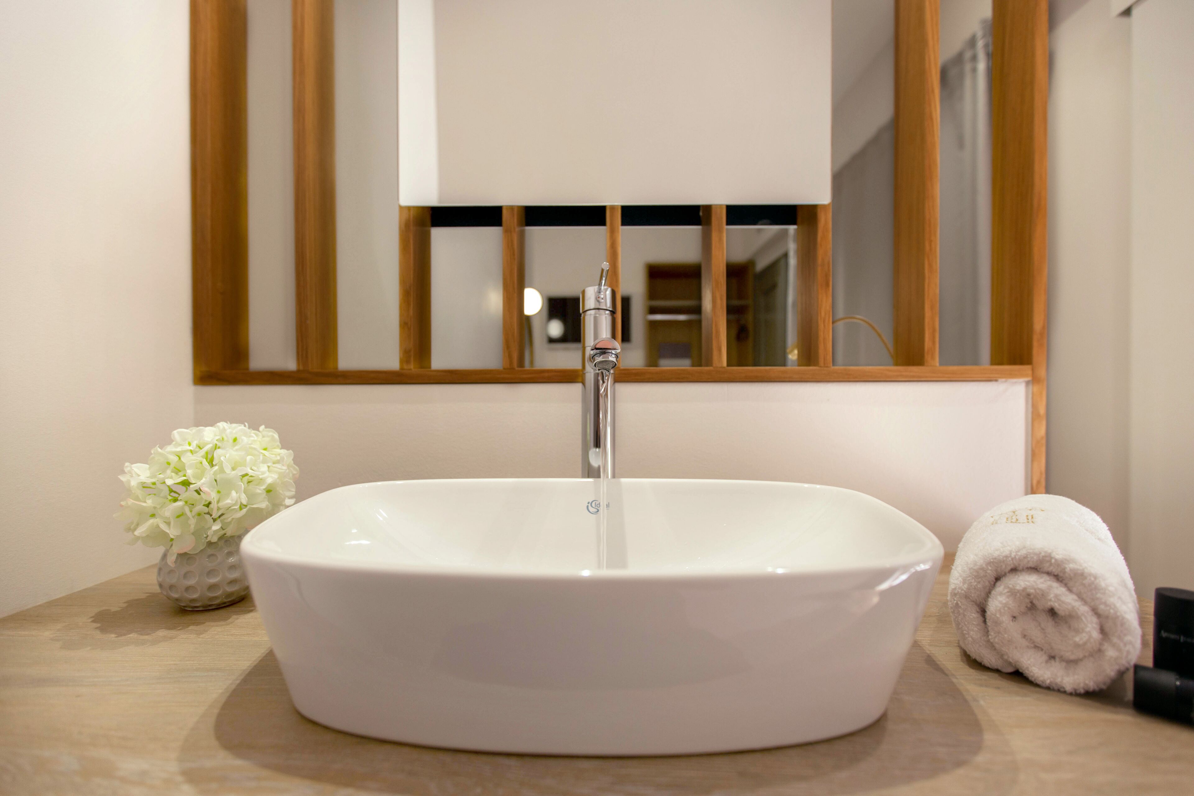 Un baño con lavamanos blanco, un espejo y una toalla.