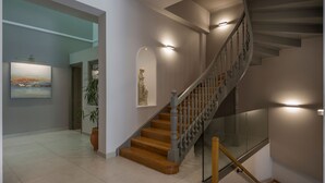 Een moderne trap met houten treden en glazen balustrades, die naar een verdieping leidt.