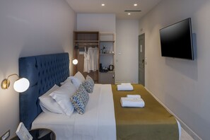 Ein modernes Hotelzimmer mit einem großen Bett, einem Kleiderschrank, einem Fernseher und einem Nachttisch.